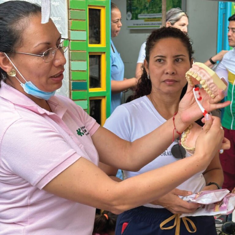 Una voluntaria enseña higiene oral con un modelo de dentadura
